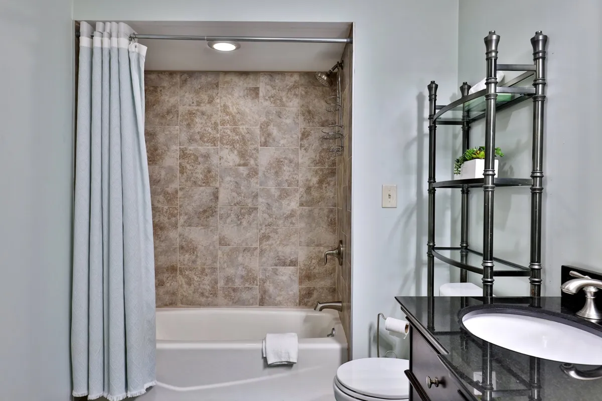 A modern bathroom with a bathtub, stylish vanity, and open shelving, creating an inviting and functional space for self-care routines. The neutral tones and clean lines evoke relaxation and privacy.