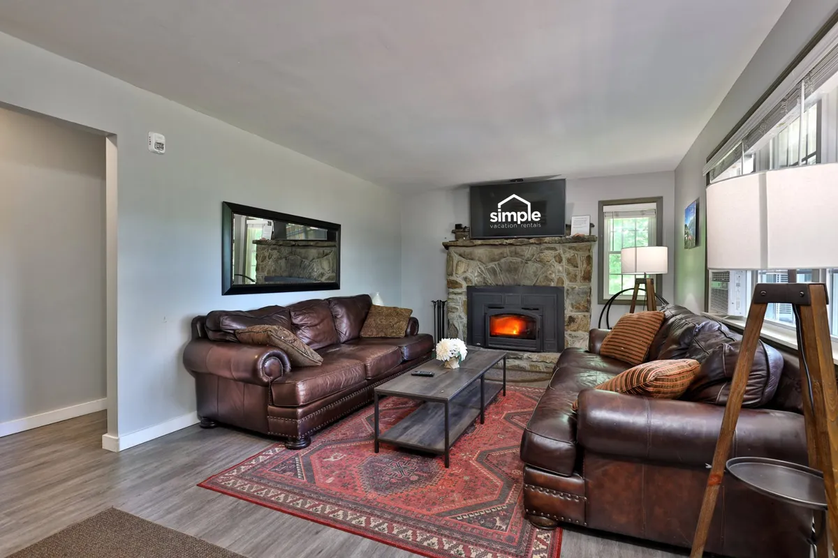A warm, inviting living room centered around a classic fireplace. Plush sofas are arranged to encourage conversation, with a coffee table and cozy rug completing the space. The room exudes a sense of comfort and is ideal for relaxing, social gatherings, or unwinding after a day of adventure.