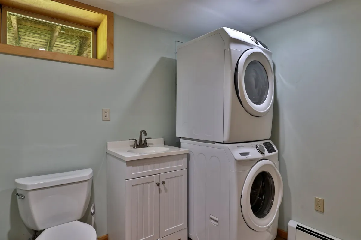A tidy laundry area complete with washing machine, dryer, sink, and a small window providing natural light. The layout is practical, ensuring convenience for extended stays and family needs.