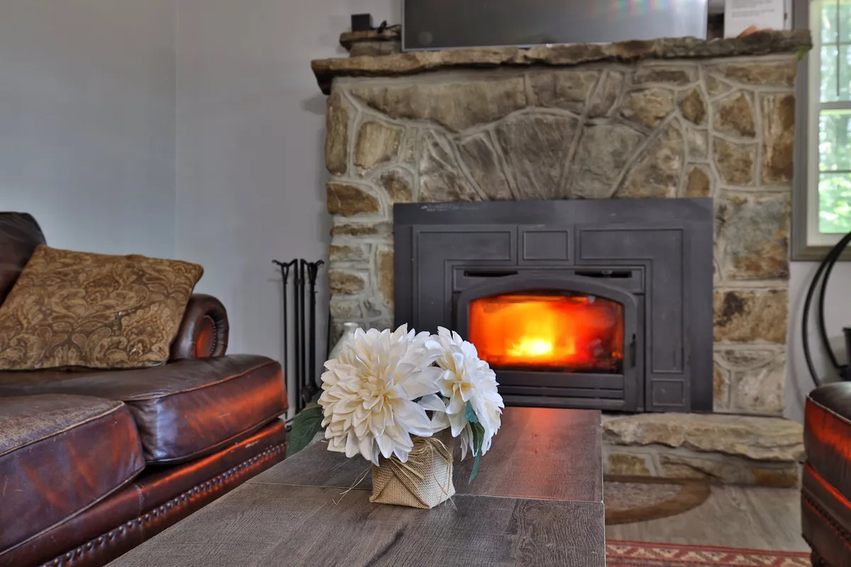 An inviting interior living space featuring a stone fireplace, leather couch, and coffee table with flowers. The ambiance is warm and welcoming, perfect for relaxing after an active day outdoors.
